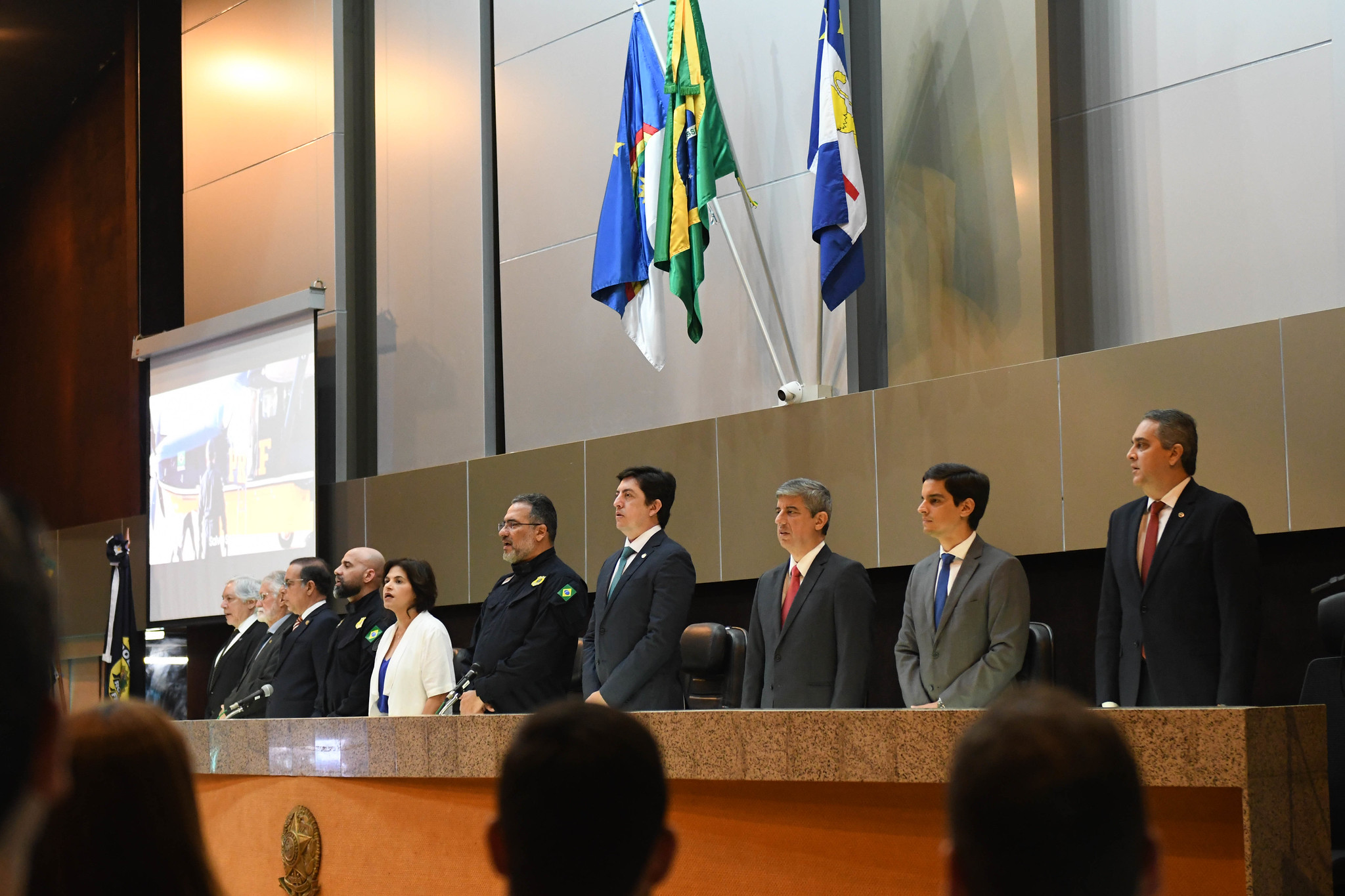 Fotografia da mesa de abertura com autoridades em pé 