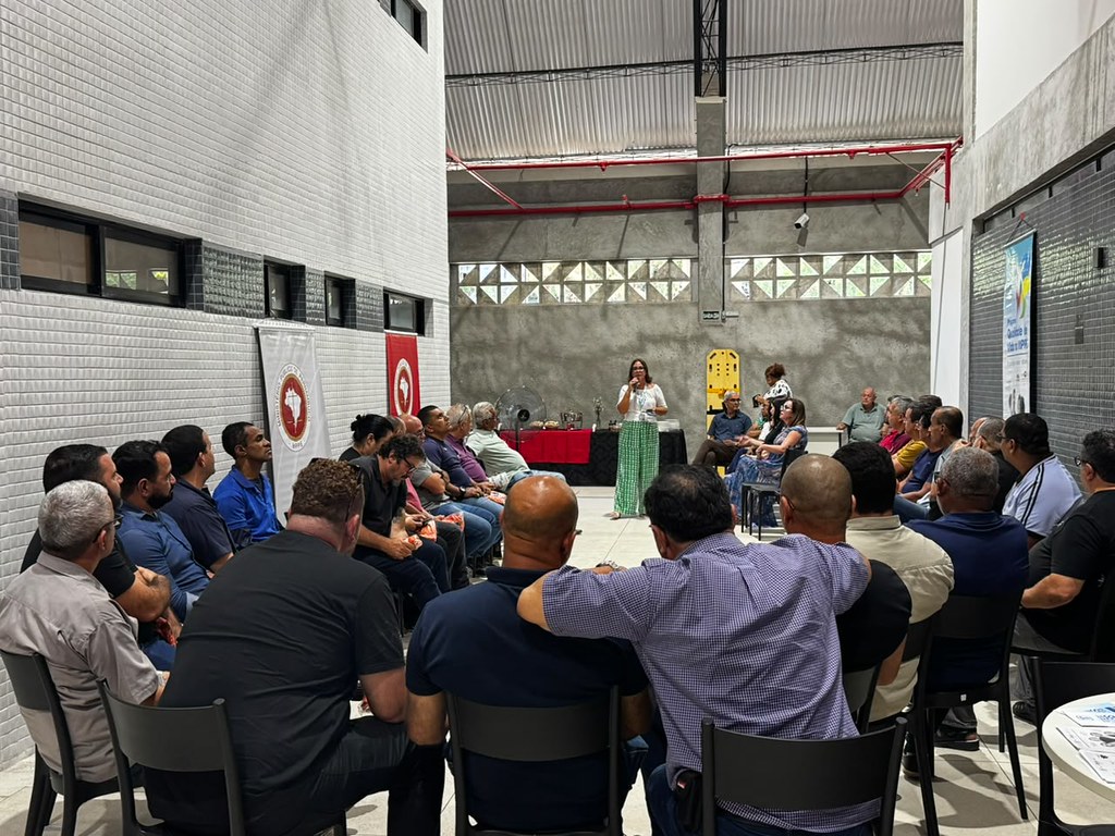 Fotografia de motoristas sentados em círculo ouvindo palestras