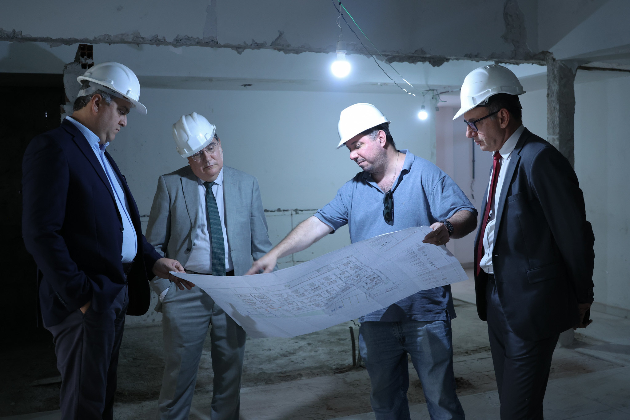 Foto dos visitantes conferindo planta em canteiro de obras