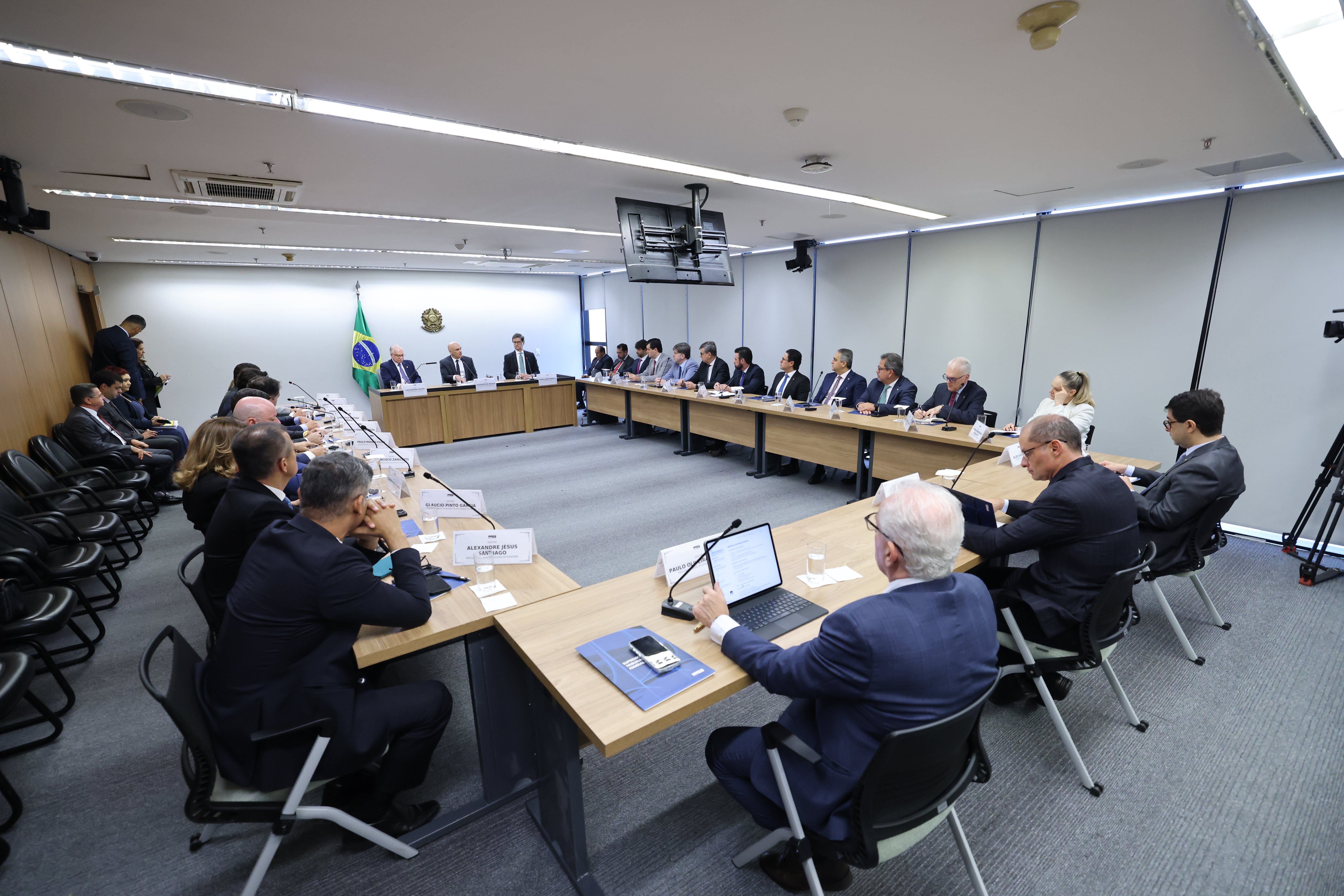 Fotografia dos participantes em volta da mesa de reunião