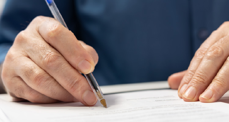 Imagem de homem escrevendo em papel sobre a mesa
