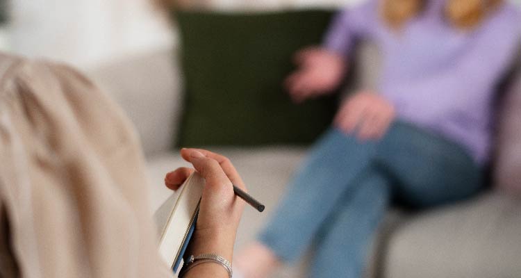 Imagem de mulher sentada ouvindo relato de paciente em consulta