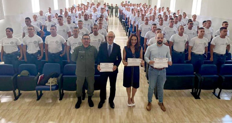 Fotografia de participantes da palestra diante de auditório com PMS em pé