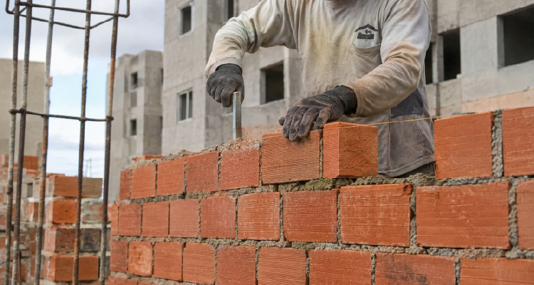 Imagem de pedreiro construindo muro de tijolos