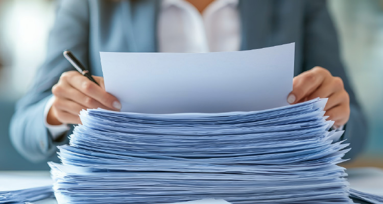 Imagem de pessoa mexendo em pilha papéis e analisando conteúdos