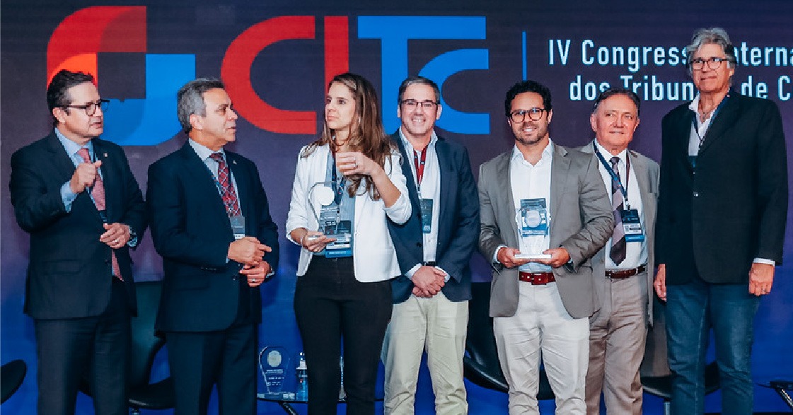 Seis homens e uma mulher aparecem de pé numa foto. As quatro pessoas do meio seguram trofeus.