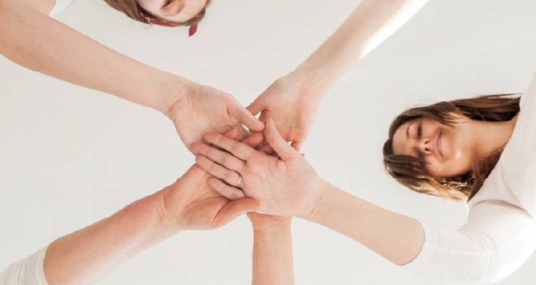 Imagem de mulheres em círculo se dando as mãos ao centro