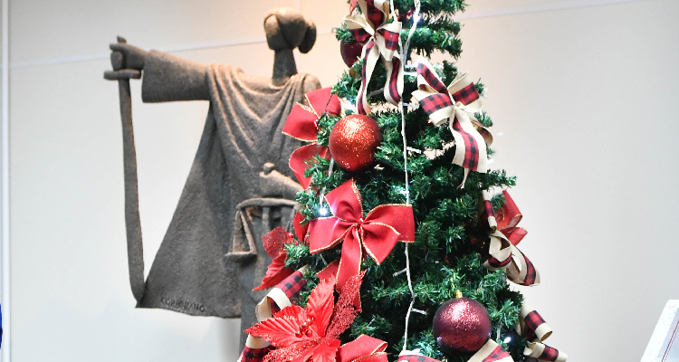Fotografia de árvore de Natal ao lado de estátua da deusa da Justiça, com cesta de presentes ao lado