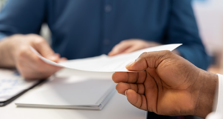 Fotografia de pessoa entregando documento a outra