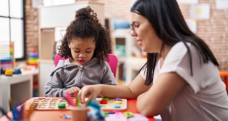 Imagem de professora brincando com criança em sala de aula