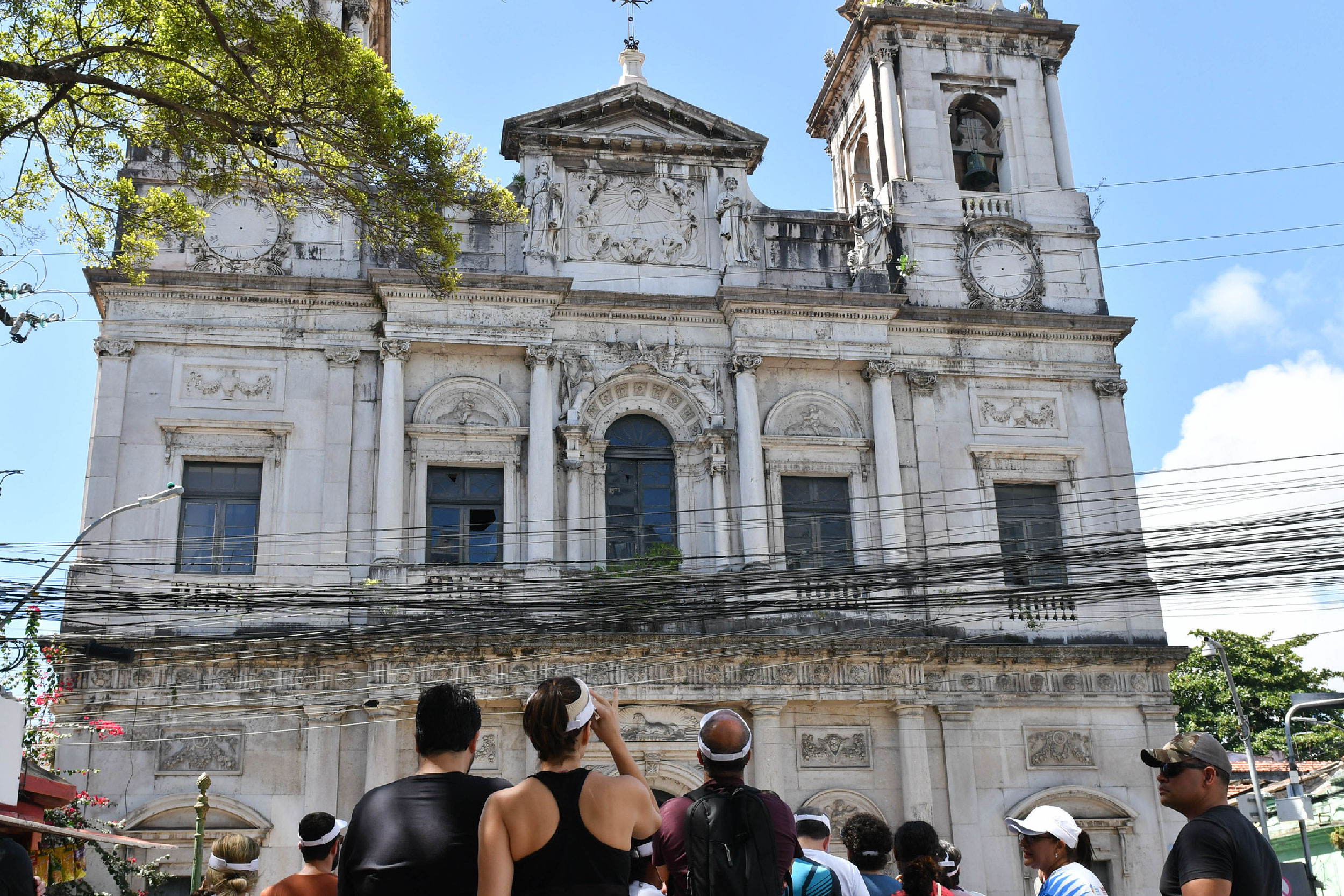 Fotografia de pessoas paradas em frente a uma igreja admirando a fachada