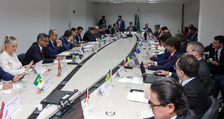 Fotografia dos participantes sentado em volta da mesa de reunião