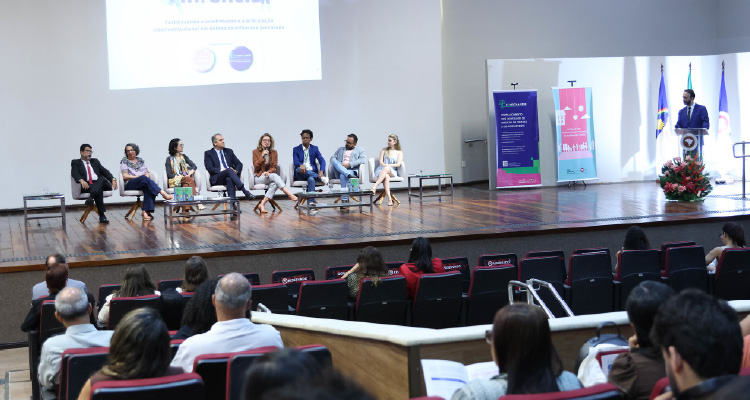 Fotografia de participantes no palco sentados e palestrando