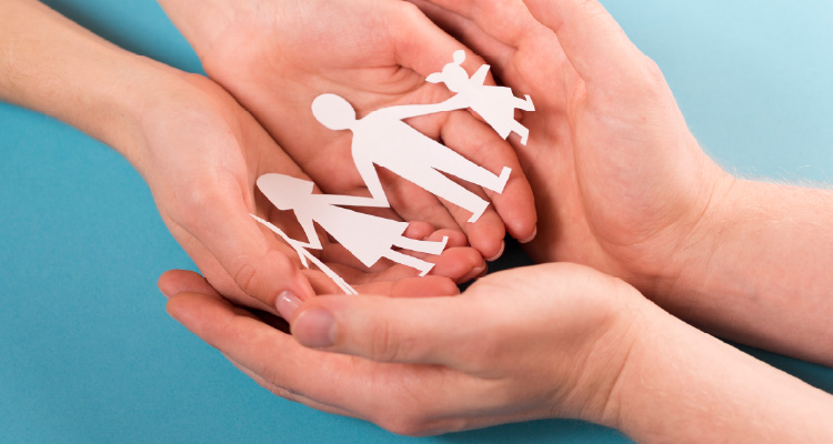 Imagem de duas mãos segurando família feita de bonecos de papel