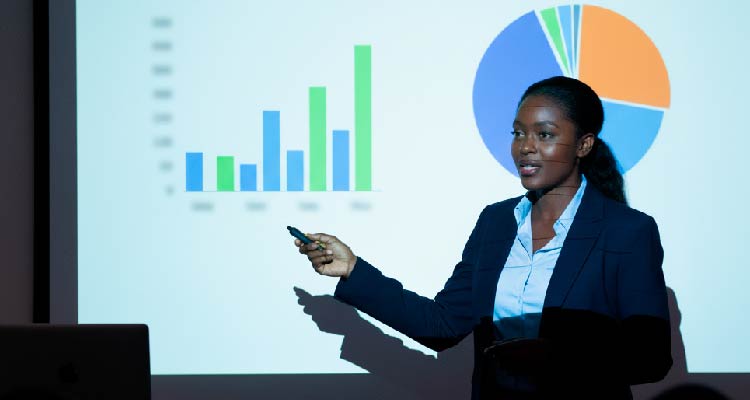Imagem de mulher negra palestrando com projeção de gráficos por trás