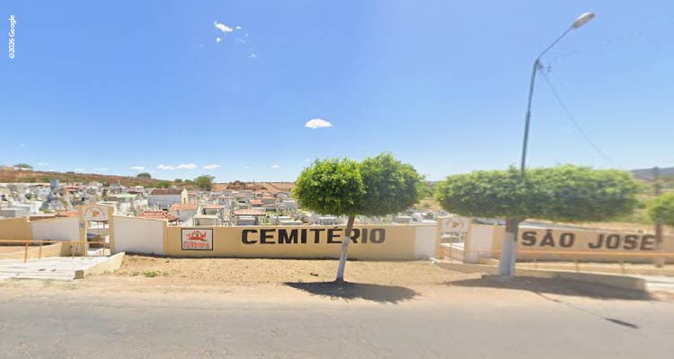 Fotografia do muro de cemitério com túmulos à vista