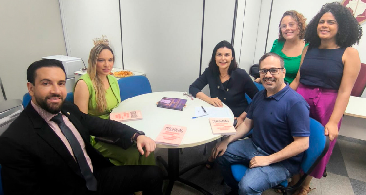 Fotografia dos integrantes do Clube do Livro em volta de mesa com livros em cima 