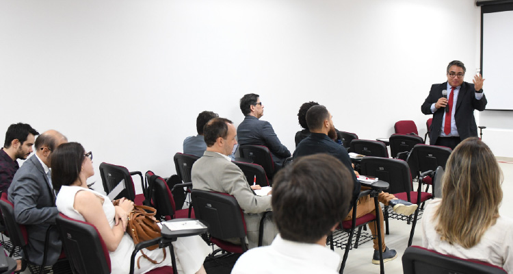 Fotografia de palestrante falando para plateia atenta