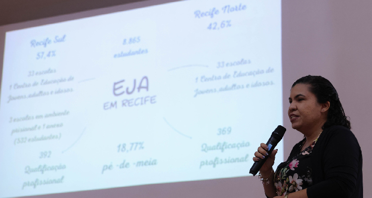 Fotografia de palestrante diante de projeção de slide