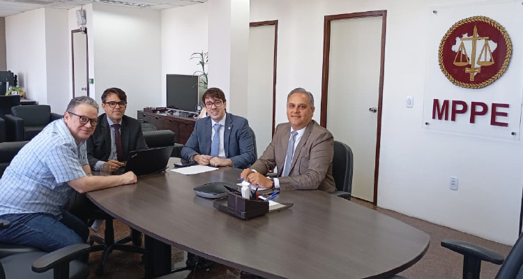 Fotografia dos integrantes da reunião sentados em volta da mesa