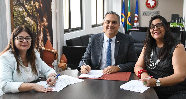 Integrantes das instituição assinando o acordo sentados à mesa