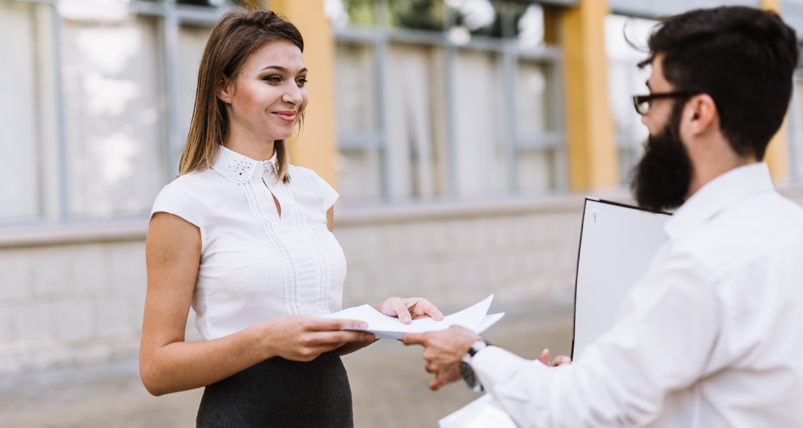 Fotografia de mulher recebendo documento de homem