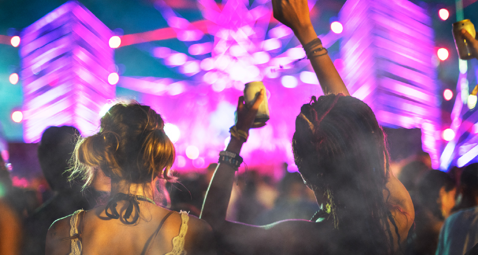 Imagem de pessoas se divertindo em frente a palco de shows iluminado