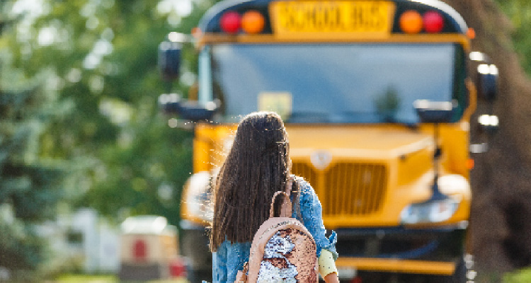 Fotografia de menina em frente a ônibus amarelo escolar