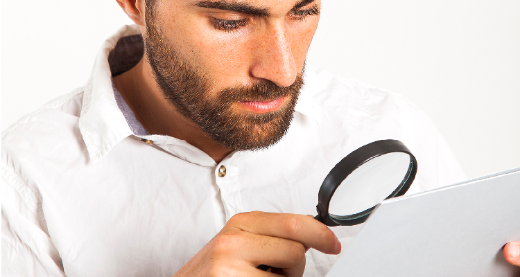 Fotografia de banco de imagens mostra homem branco usando lupa para averiguar  documento