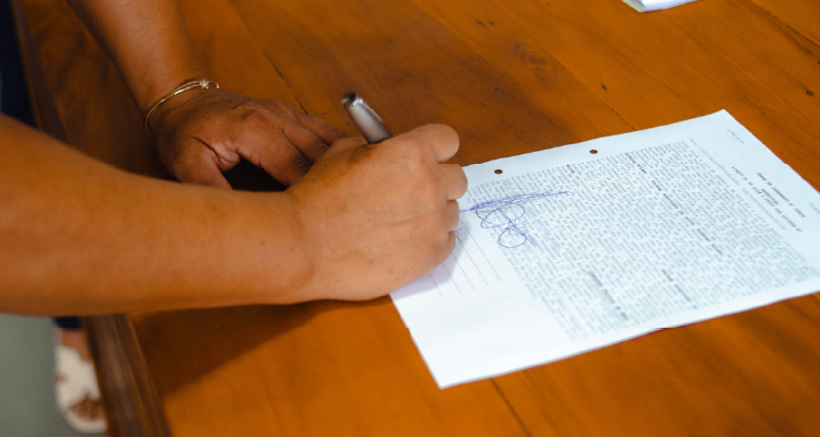 Imagem de pessoa assinando documento