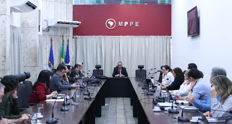 Fotografia de integrantes da reunião sentados em volta da mesa de discussão