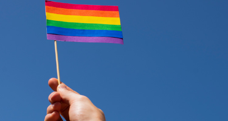 Fotografia de mão levantando bandeira do arco-íris
