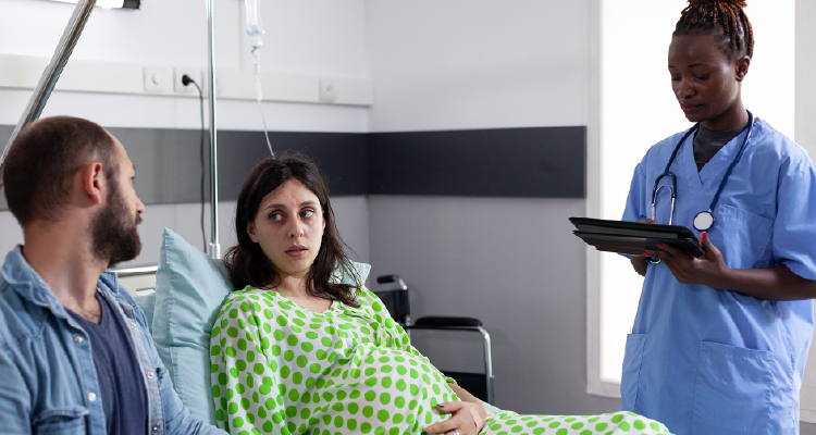 Imagem de mulher deitada em cama hospitalar sendo atendida por equipe médica