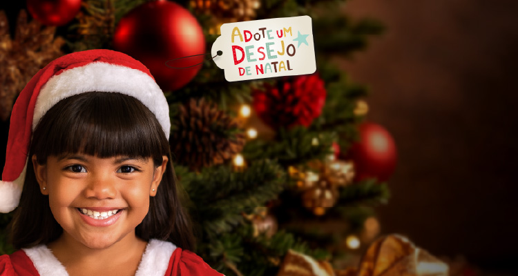 Imagem de menina vestida de papai noel em frente à árvore de natal