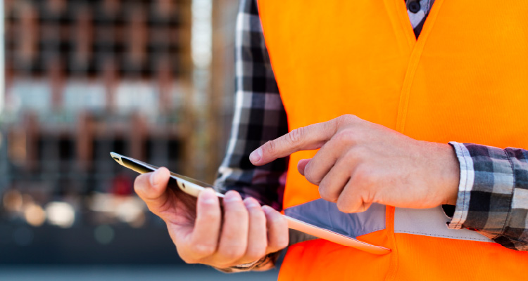Imagem de homem usando colete laranja de proteção e segurando prancheta