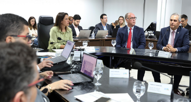 Fotografia de participantes do evento sentados em mesa circular 