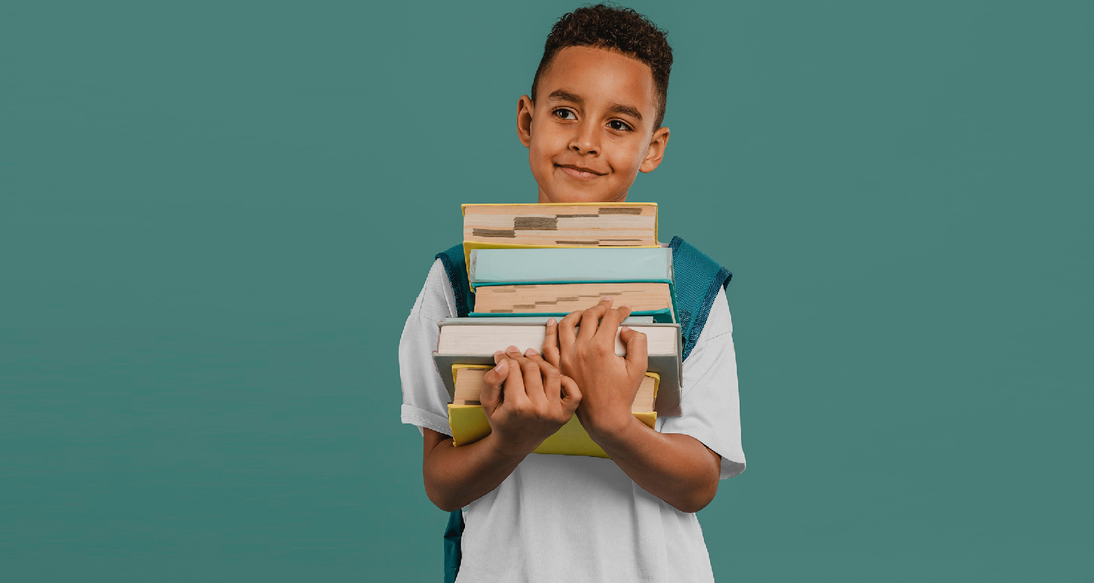 Fotografia de menino negro com mochila nas costas e segurando livros e cadernos com as duas mãos