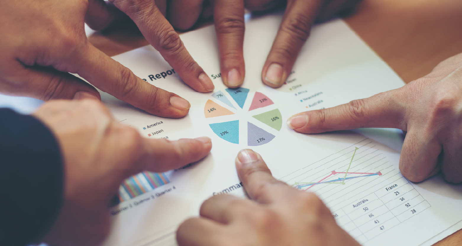 Fotografia de vários dedos apontando gráficos em papel