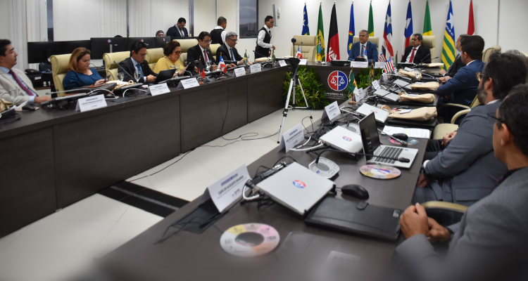 Imagem da sala de reunião com participantes sentados à mesa