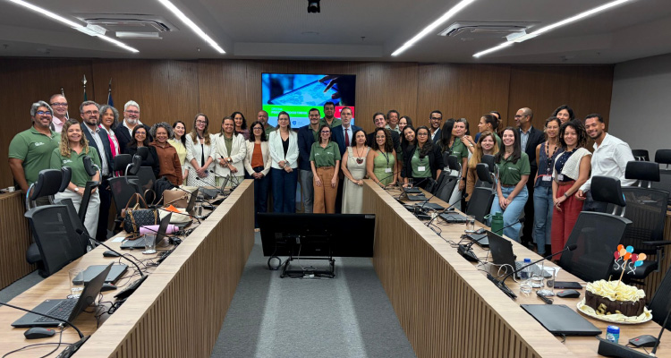 Fotografia dos participantes do evento posando juntos em volta da mesa de discussões