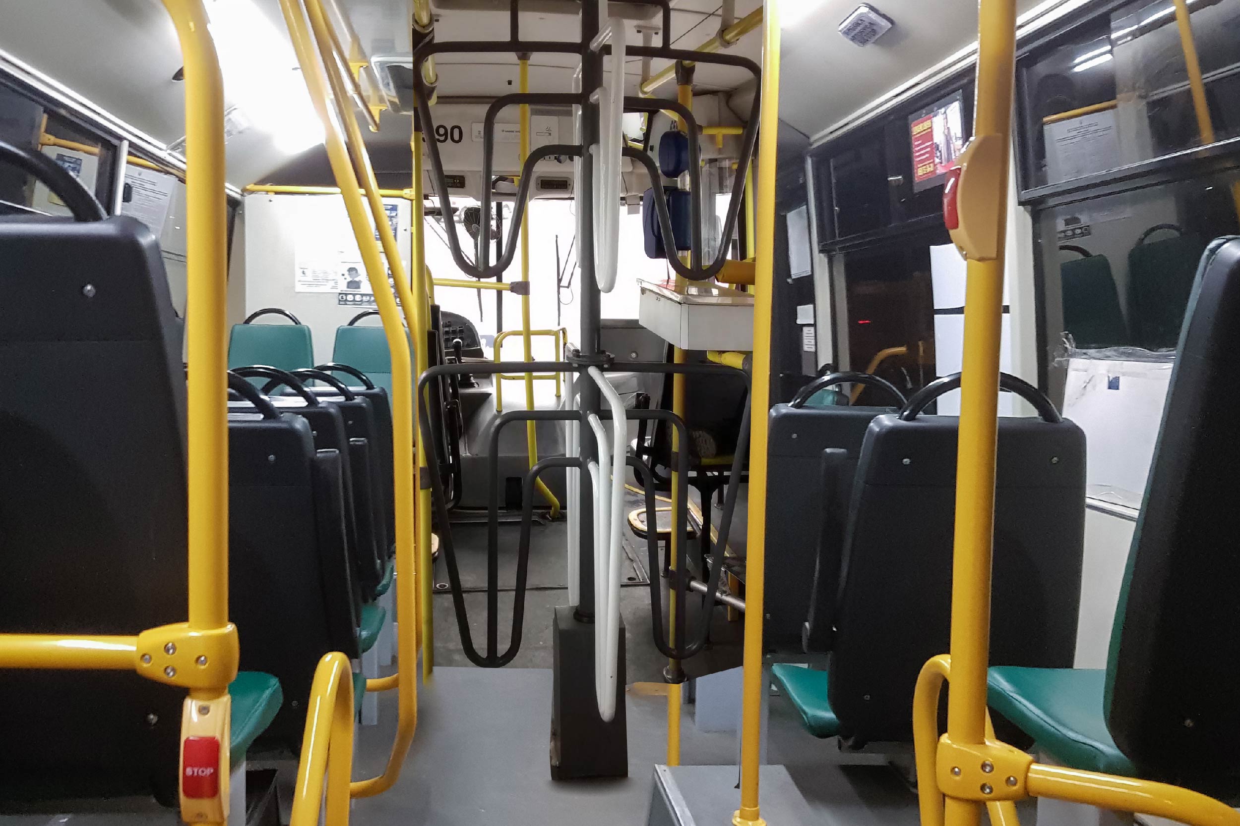 Foto mostra o interior de um ônibus. Bem no meio, está instalada uma catraca dupla, ladeada por cadeiras