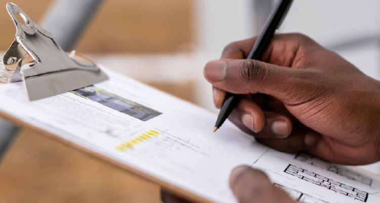 Fotografia de mão segurando lápis e preenchendo formulário em prancheta