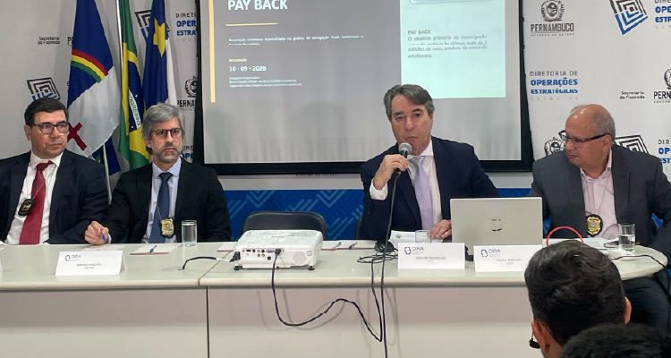 Fotografia dos organizadores sentados à mesa diante dos jornalistas