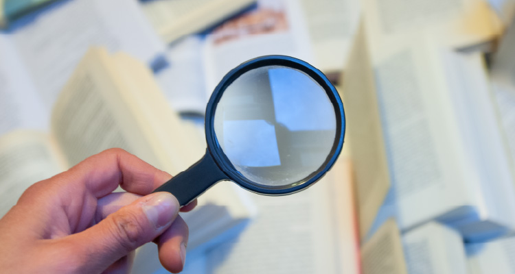 Imagem de lupa investigativa diante de documentos impressos