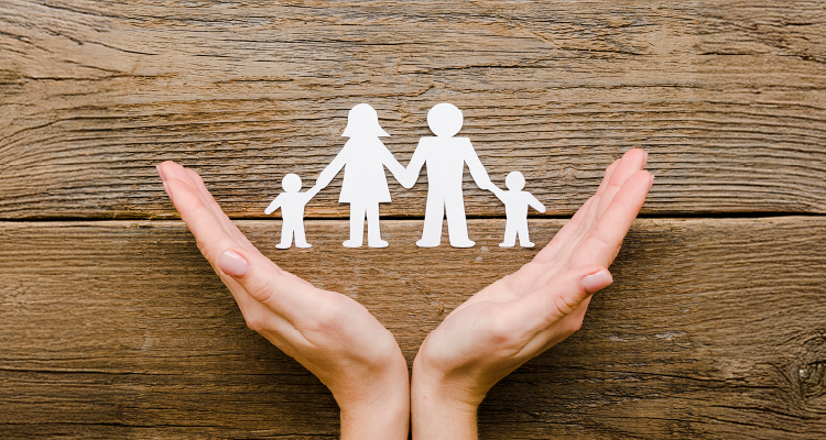 Uma foto com as mãos em V com uma representação de família em recorte de papel