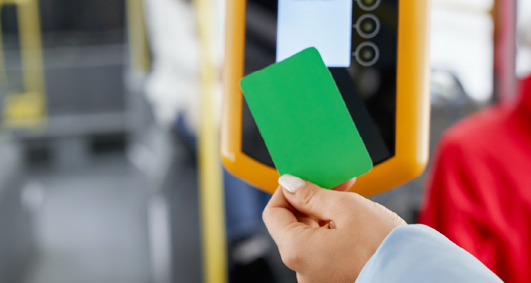 Imagem de pessoa segurando cartão perto a equipamento de ônibus de conferir passagens