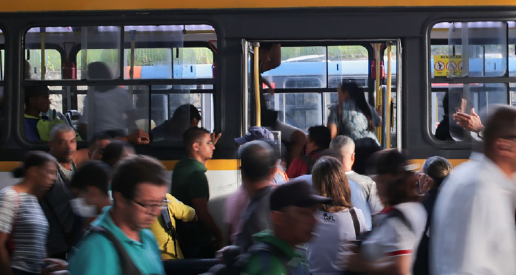 Imagem de pessoas em volta de ônibus em um terminal
