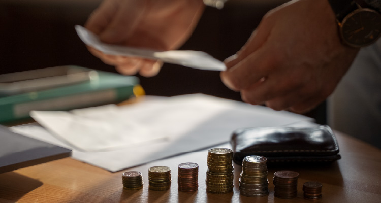 Fotografia de pessoa mexendo em papéis com moedas ao lado