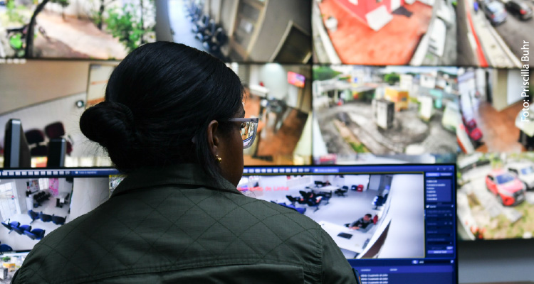 Imagem de policial conferindo câmeras de segurança através de monitores