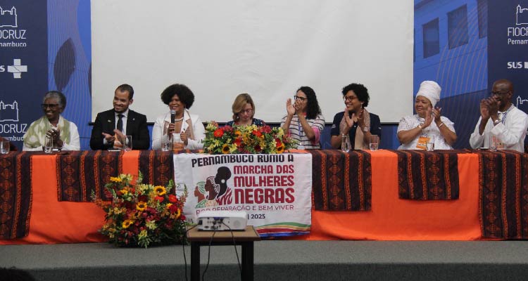 Fotografia de pessoas sentadas à mesa principal do evento